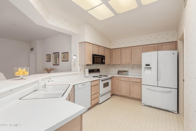 kitchen with light brown cabinets, white appliances, a sink, light floors, and wallpapered walls