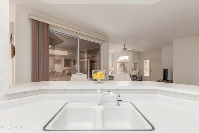 kitchen featuring ceiling fan, light countertops, a sink, and open floor plan