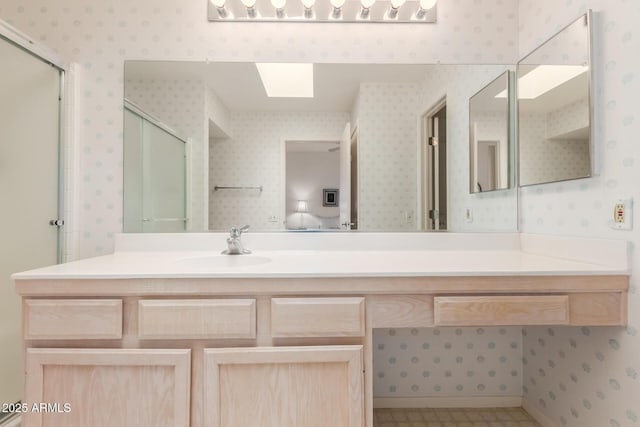 ensuite bathroom featuring ensuite bathroom, a skylight, vanity, an enclosed shower, and wallpapered walls