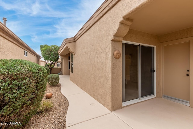 view of exterior entry featuring a patio area and stucco siding