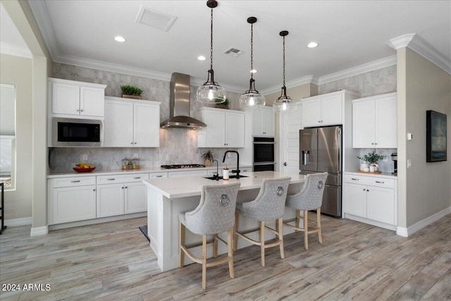 kitchen with appliances with stainless steel finishes, hanging light fixtures, backsplash, sink, and wall chimney exhaust hood