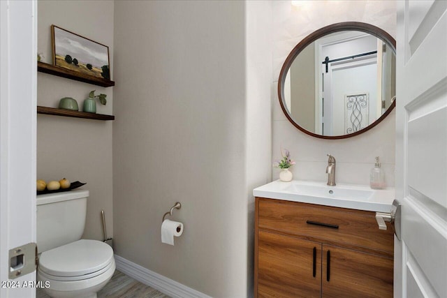 bathroom with hardwood / wood-style flooring, toilet, and vanity