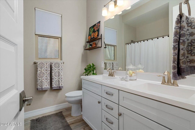 bathroom with double sink vanity, toilet, and hardwood / wood-style flooring