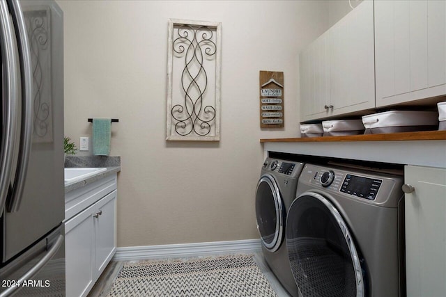 clothes washing area featuring cabinets, wood-type flooring, and washer and dryer