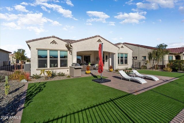 rear view of property featuring a yard, a patio area, and an outdoor kitchen