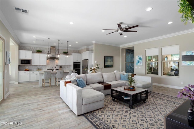 living room with light hardwood / wood-style flooring, ceiling fan, and crown molding