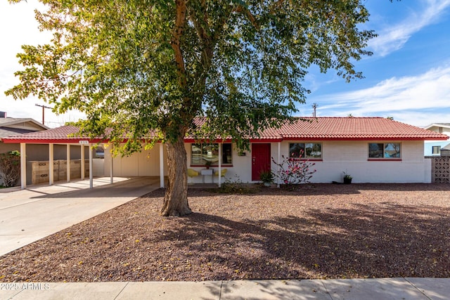 ranch-style home with concrete driveway, an attached carport, and a tile roof