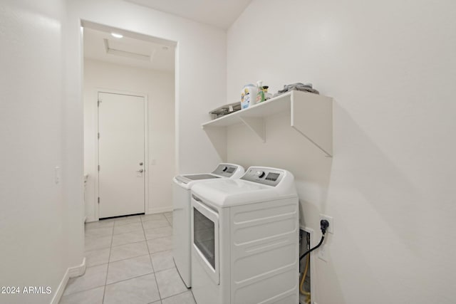 clothes washing area featuring laundry area, attic access, light tile patterned floors, baseboards, and washing machine and clothes dryer