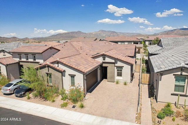 view of front of property featuring a mountain view, a tile roof, decorative driveway, a gate, and stucco siding