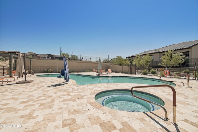 community pool featuring a patio area, a hot tub, and fence