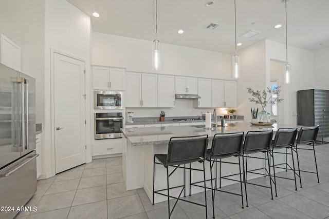 kitchen with visible vents, a high ceiling, appliances with stainless steel finishes, a sink, and under cabinet range hood