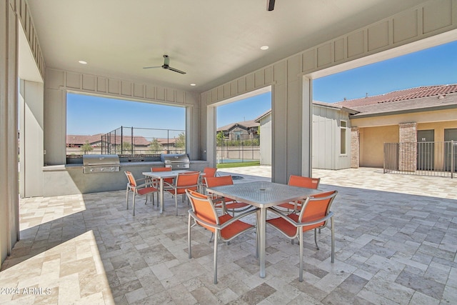 view of patio / terrace featuring a ceiling fan, area for grilling, fence, exterior kitchen, and outdoor dining space