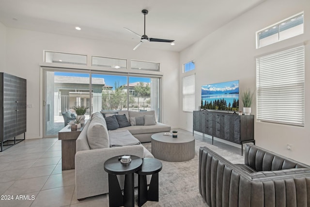 living area featuring light tile patterned floors, baseboards, a ceiling fan, a high ceiling, and recessed lighting