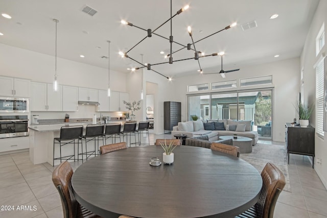 dining space with a towering ceiling, light tile patterned floors, and visible vents