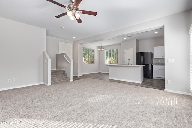 unfurnished living room featuring ceiling fan with notable chandelier, dark hardwood / wood-style floors, and sink