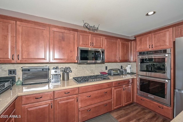 10806 W Adam Ave, Peoria, AZ 85373 - kitchen with appliances with stainless steel finishes, light countertops, dark wood finished floors, tasteful backsplash, and brown cabinetry