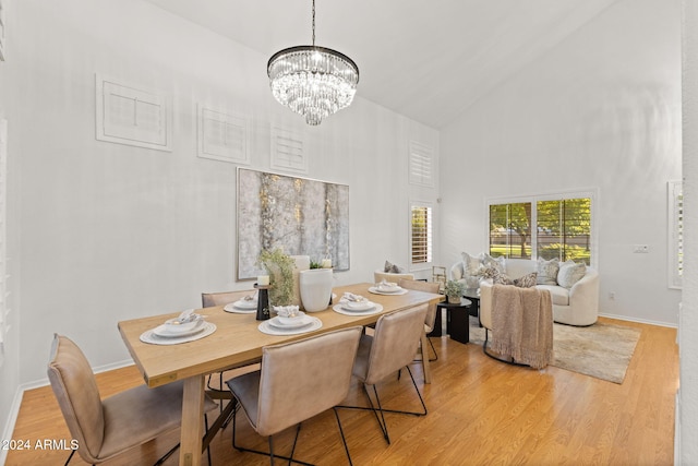 dining room featuring a chandelier, high vaulted ceiling, and light hardwood / wood-style floors