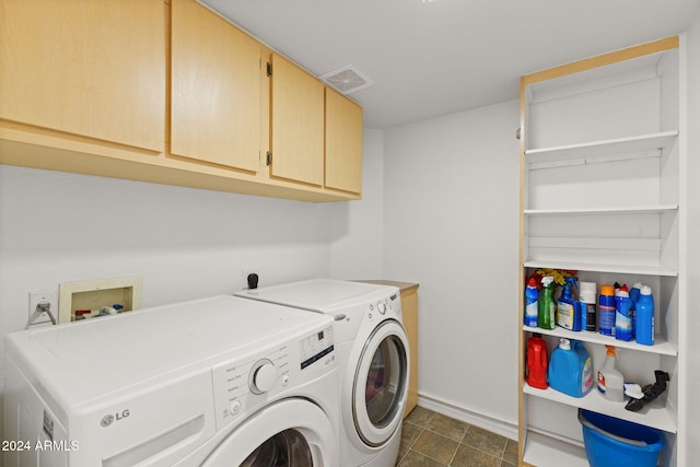 clothes washing area with cabinets, separate washer and dryer, and dark tile patterned flooring