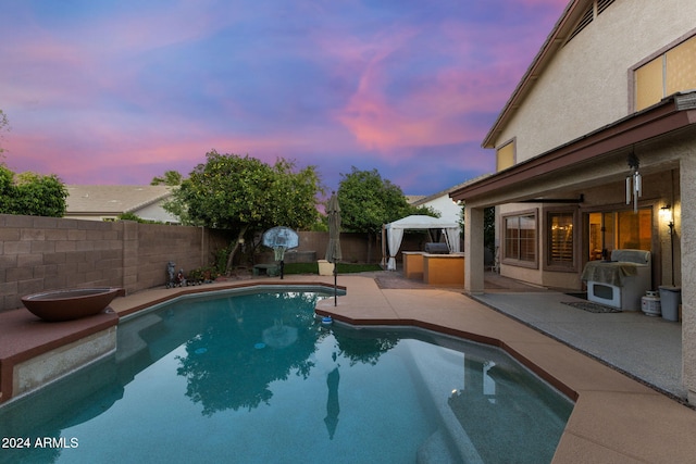 pool at dusk featuring a patio