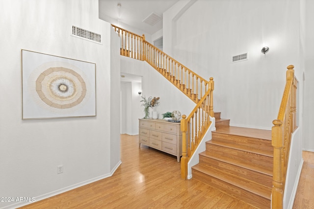 stairs with a towering ceiling and wood-type flooring