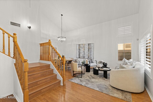 living room featuring high vaulted ceiling, wood-type flooring, and a notable chandelier