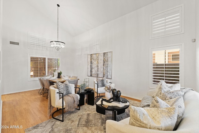 living room featuring hardwood / wood-style floors, high vaulted ceiling, and a notable chandelier