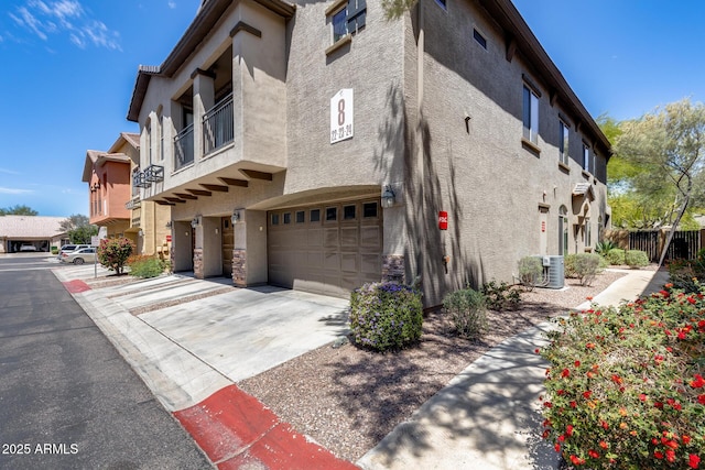 exterior space featuring an attached garage, stucco siding, driveway, and fence