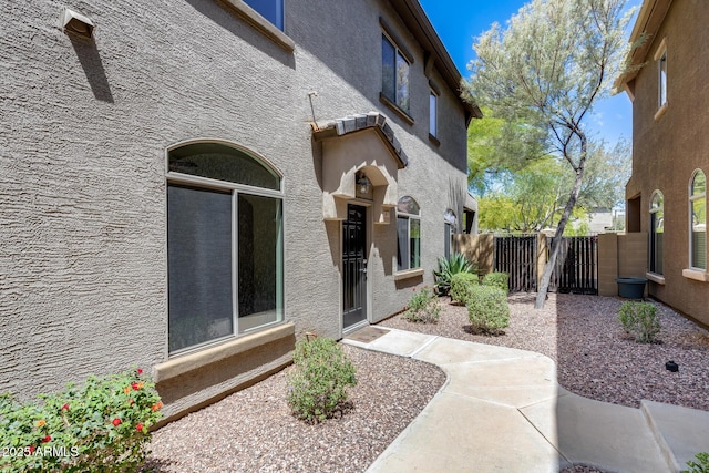 view of exterior entry featuring fence and stucco siding