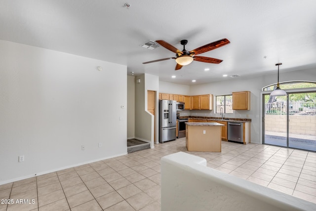 kitchen featuring light tile patterned flooring, a kitchen island, ceiling fan, a sink, and stainless steel appliances