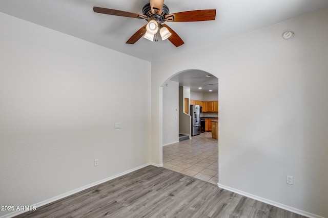 spare room with ceiling fan, arched walkways, recessed lighting, baseboards, and light wood-type flooring