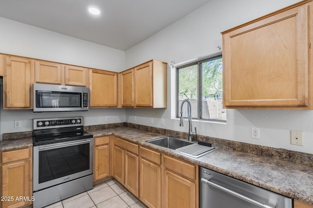 kitchen featuring stainless steel appliances, dark countertops, light tile patterned flooring, and a sink