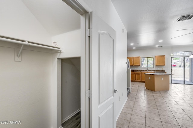 kitchen with brown cabinetry, visible vents, light tile patterned floors, a sink, and recessed lighting