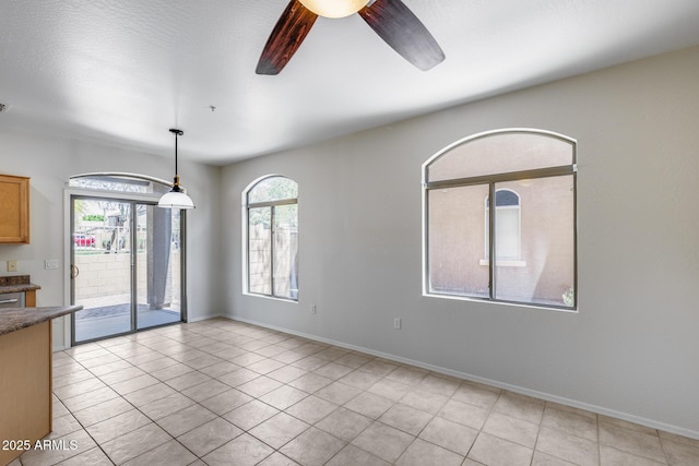 spare room featuring baseboards, a ceiling fan, and light tile patterned flooring