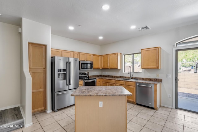 kitchen featuring visible vents, appliances with stainless steel finishes, a center island, a sink, and a wealth of natural light