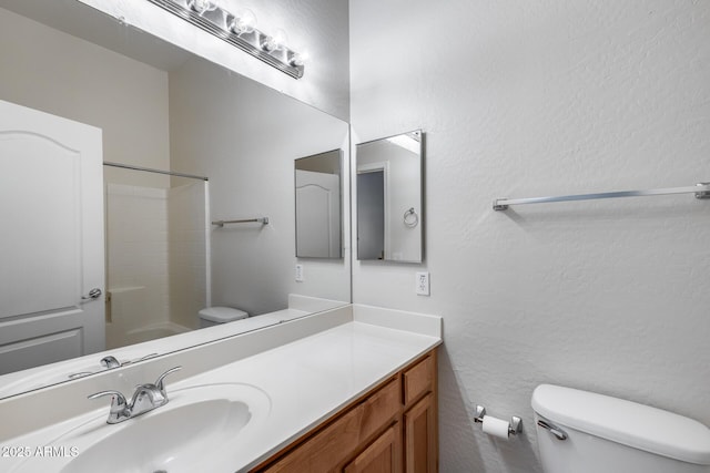 bathroom with vanity, a textured wall, and toilet