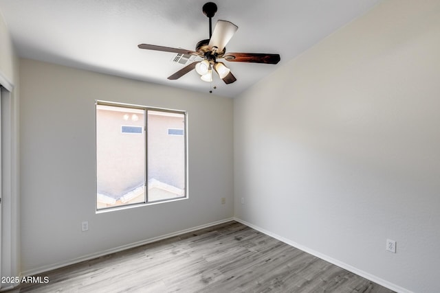 empty room featuring a ceiling fan, baseboards, visible vents, and light wood finished floors