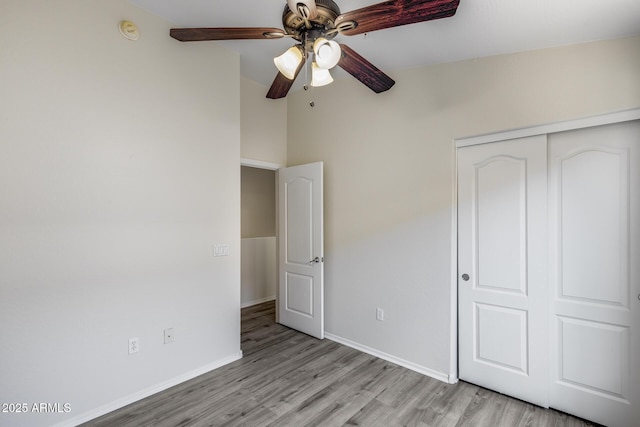 unfurnished bedroom with light wood-style floors, a ceiling fan, baseboards, and a closet