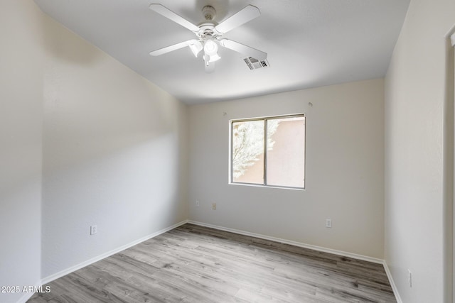 spare room featuring baseboards, ceiling fan, visible vents, and wood finished floors