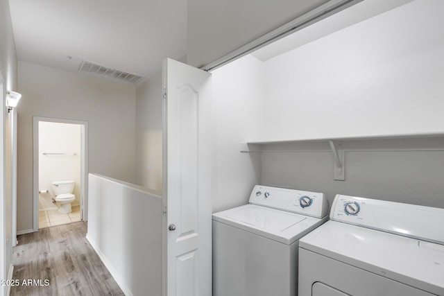 washroom with washing machine and clothes dryer, laundry area, light wood finished floors, and visible vents
