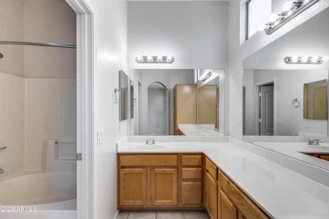 full bath featuring double vanity,  shower combination, a sink, and tile patterned flooring