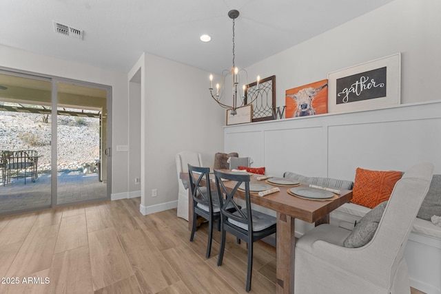 dining space with light hardwood / wood-style flooring and a chandelier