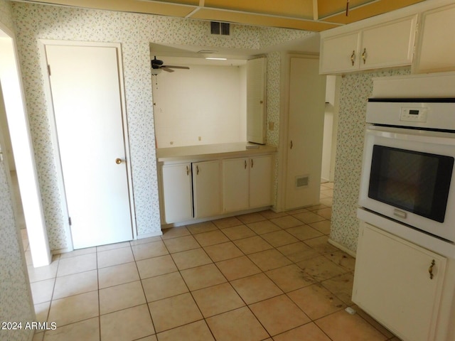 kitchen featuring white oven, white cabinets, ceiling fan, and light tile patterned floors