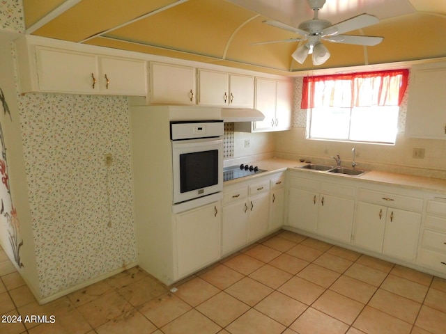 kitchen featuring white oven, black electric cooktop, sink, and white cabinets