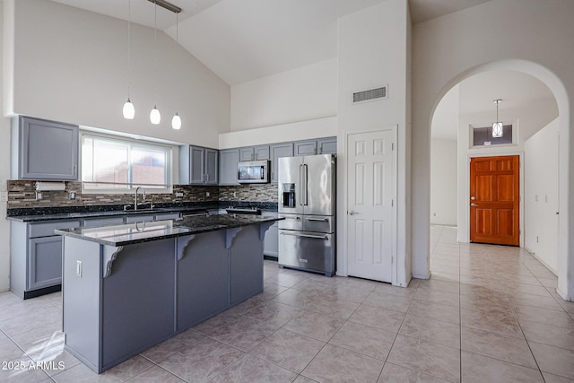 kitchen featuring decorative light fixtures, a center island, dark stone counters, and appliances with stainless steel finishes