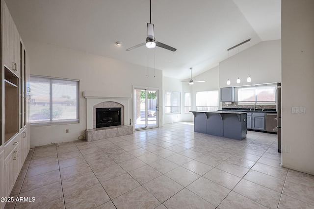 kitchen featuring a breakfast bar area, a center island, light tile patterned floors, gray cabinets, and a fireplace