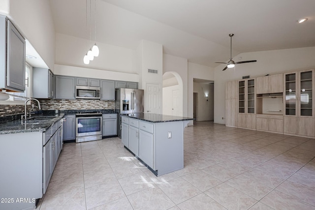 kitchen featuring sink, appliances with stainless steel finishes, gray cabinets, a kitchen island, and pendant lighting