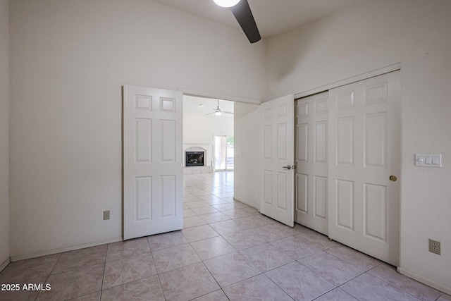 unfurnished bedroom featuring light tile patterned floors, a closet, ceiling fan, and a high ceiling