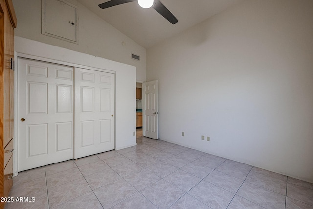 unfurnished bedroom featuring light tile patterned flooring, ceiling fan, high vaulted ceiling, and a closet