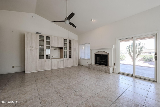 unfurnished living room featuring a tiled fireplace, light tile patterned flooring, high vaulted ceiling, and ceiling fan