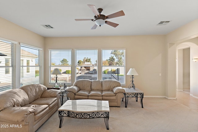 living room featuring plenty of natural light, visible vents, arched walkways, and light colored carpet